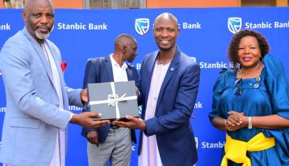 Stephen Segujja (R) Head, Economic Enterprise Restart Fund (EERF) and Cathering Poran, the CE Stanbic Business Incubator handing over a gift to the Rt. Hon. Joseph Muvawala the Prime Minister of Busog